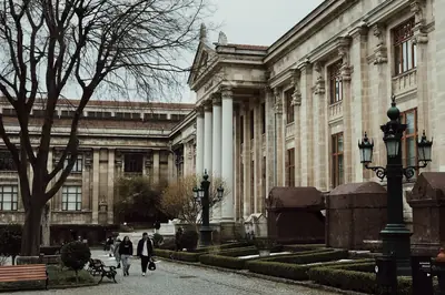 Exterior view of the Istanbul Archaeological Museums with visitors walking along a cobblestone path.