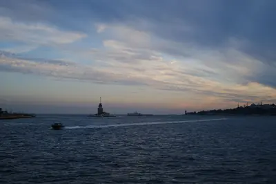 Stunning sunset view of İstanbul's Maiden's Tower with boats in the foreground, capturing a serene seascape.