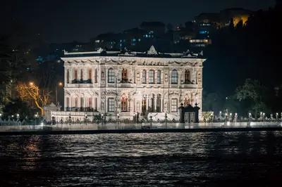 Stunning view of the illuminated Küçüksu Pavilion by the Bosporus Strait in Istanbul at night.
